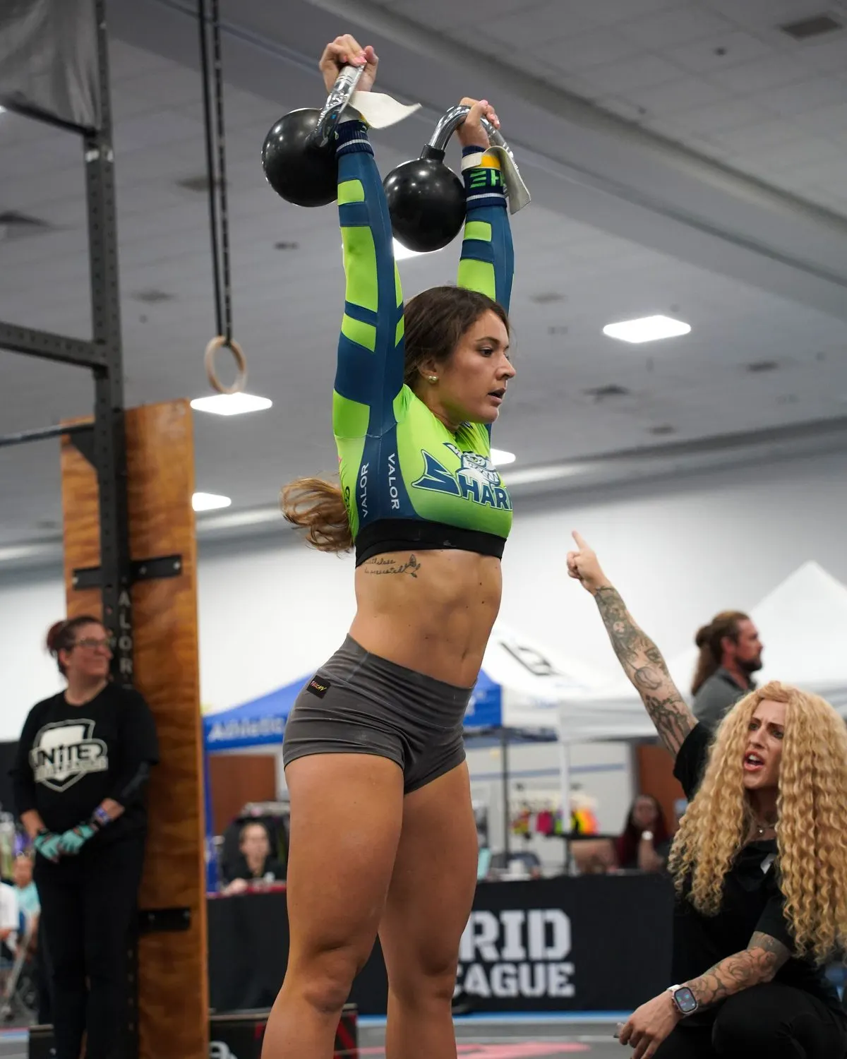 An SWFL Sharks athlete locks out two kettlebells overhead while a judge counts the rep at the Grid League match day in Lakeland.