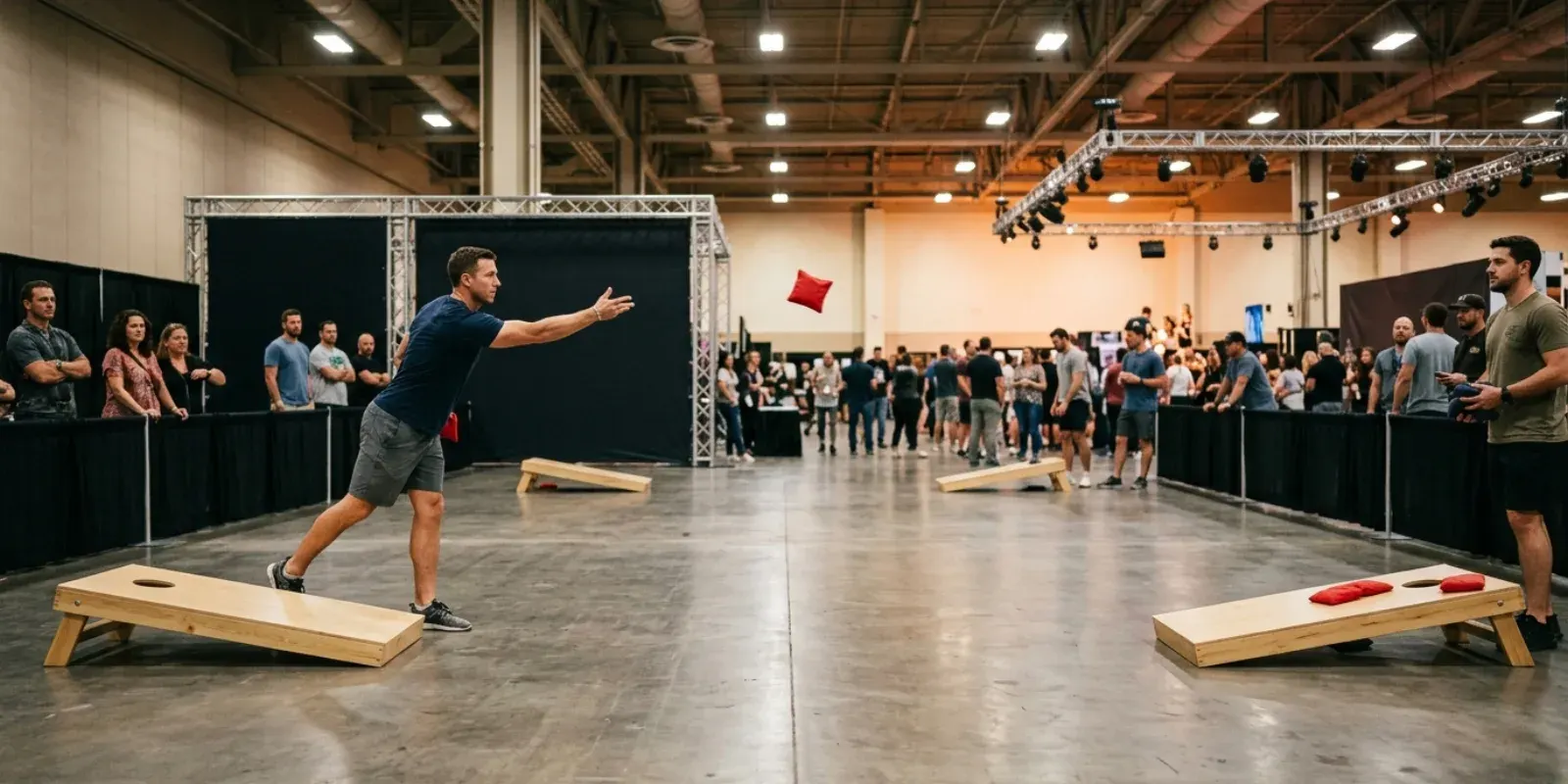 Players throwing bags down a cornhole lane on an indoor expo floor