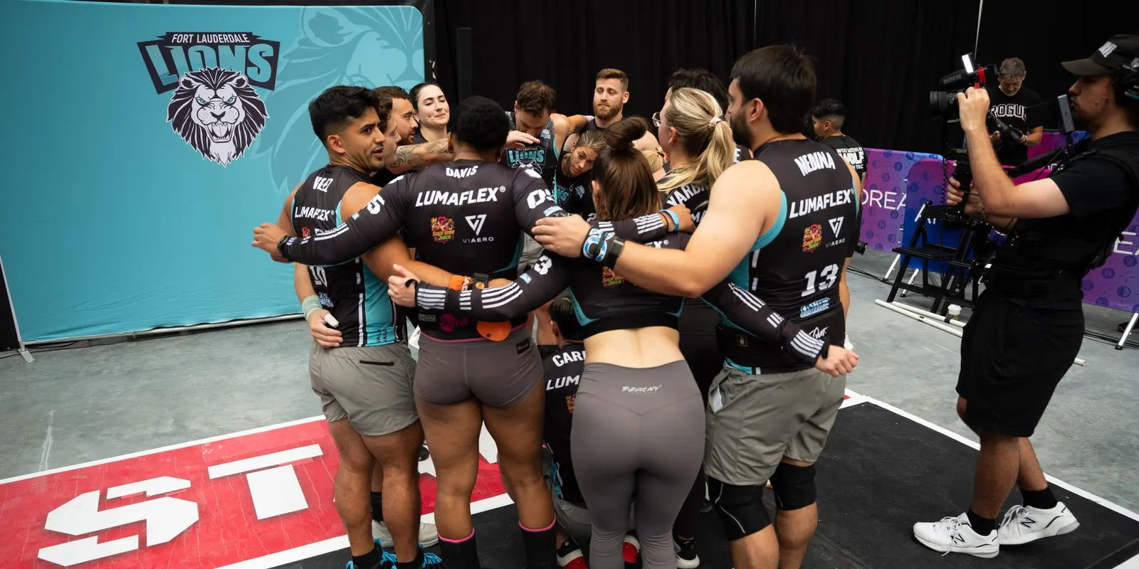 Fort Lauderdale Lions athletes huddle beneath the team banner at United Grid League Week 3 at American Dream.