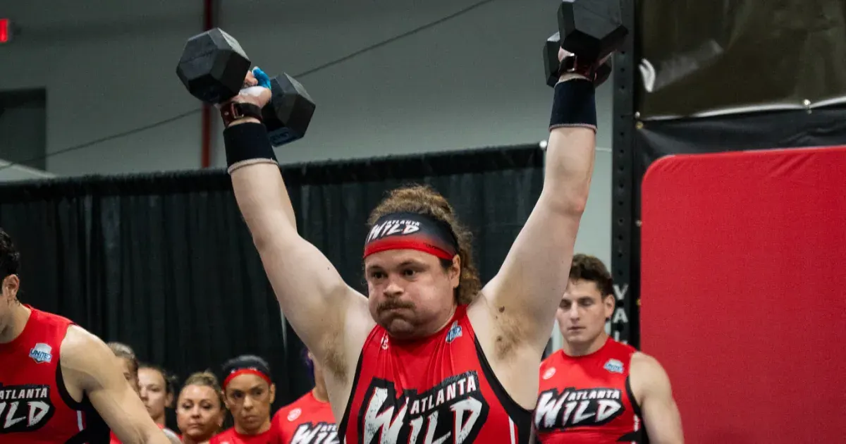 An Atlanta Wild athlete locks out a pair of dumbbells overhead during the 2026 United Grid League opening day in Miami.