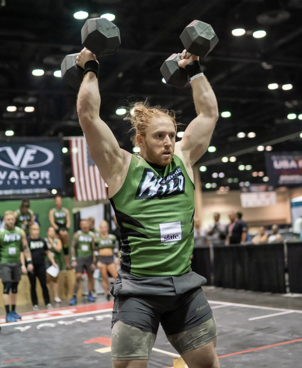 Griffin Roelle presses a pair of dumbbells overhead during a Grid League match