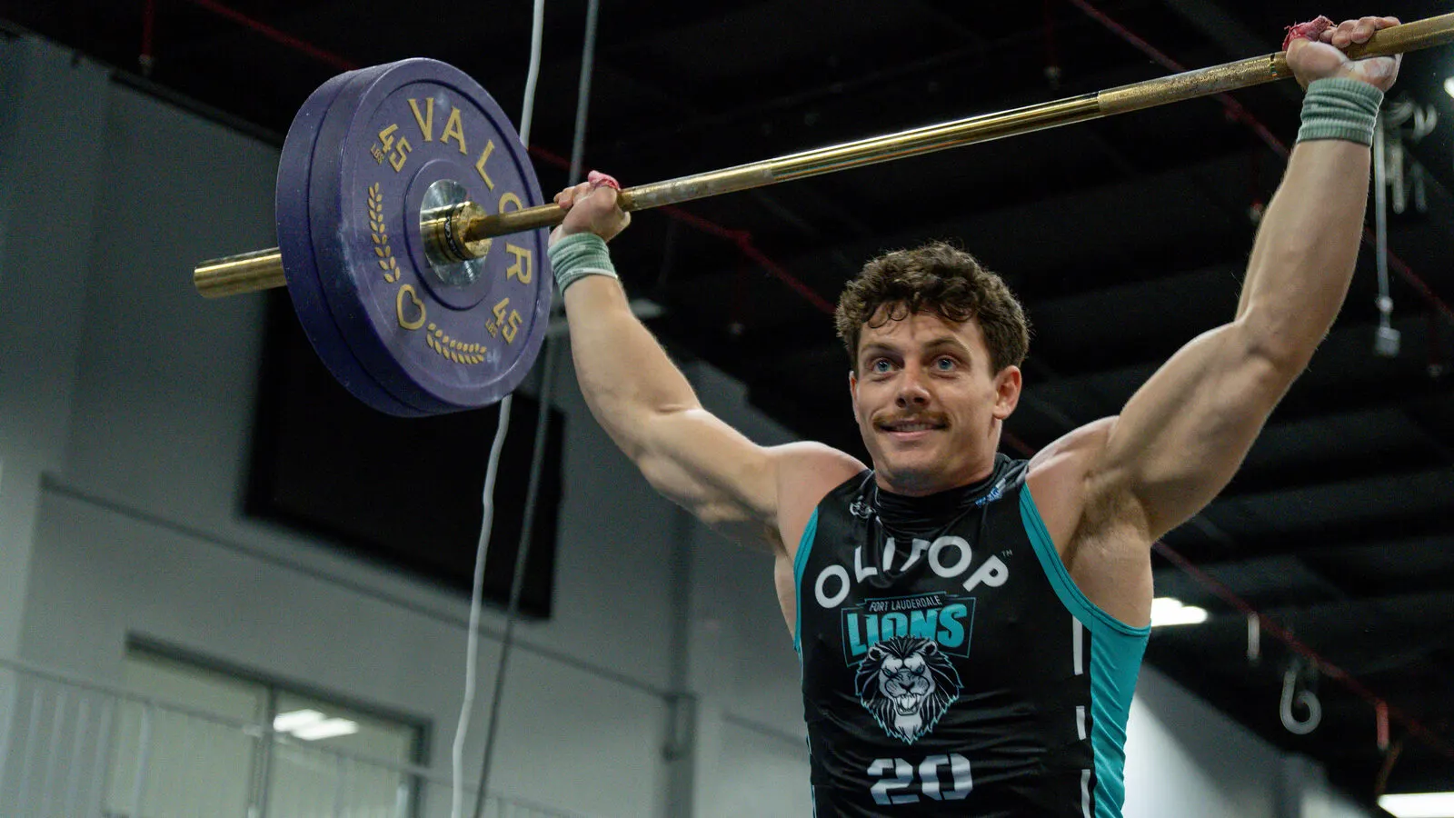 Fort Lauderdale Lions player presses a barbell overhead during a race