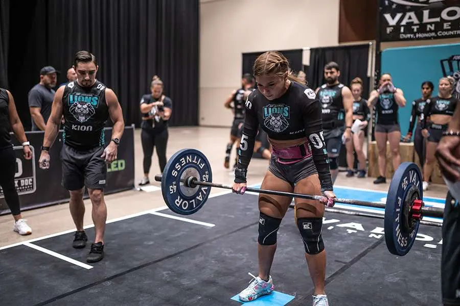 A Fort Lauderdale Lions player sets up a barbell deadlift as a teammate watches on the Grid in 2023