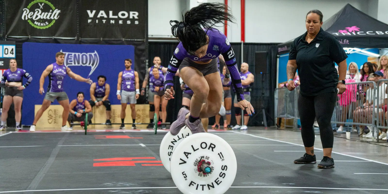 A Las Vegas Venom player leaps over the barbell during a race as teammates watch from the bench.